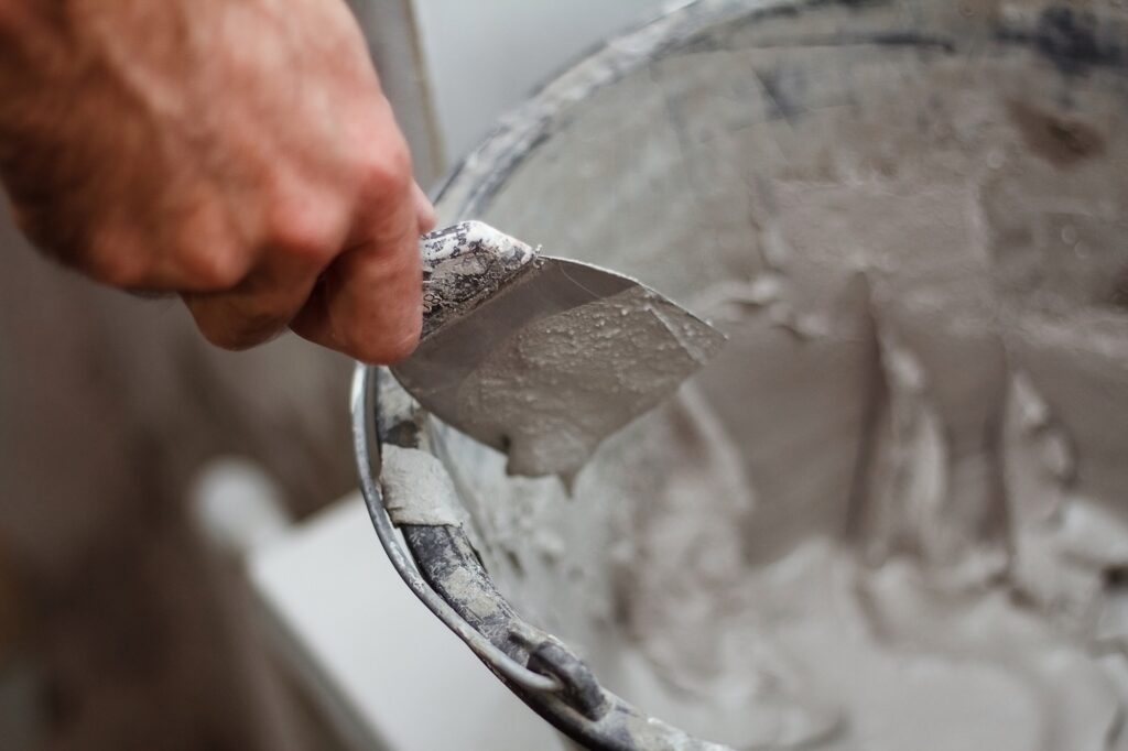 man's hand picks up plaster on a spatul
